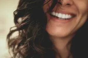 Photo by Lesly Juarez on Unsplash https://unsplash.com/photos/long-black-haired-woman-smiling-close-up-photography-1AhGNGKuhR0 - woman smiling, healthy dental implants